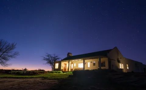A lit stone cottage beneath a starry night sky
