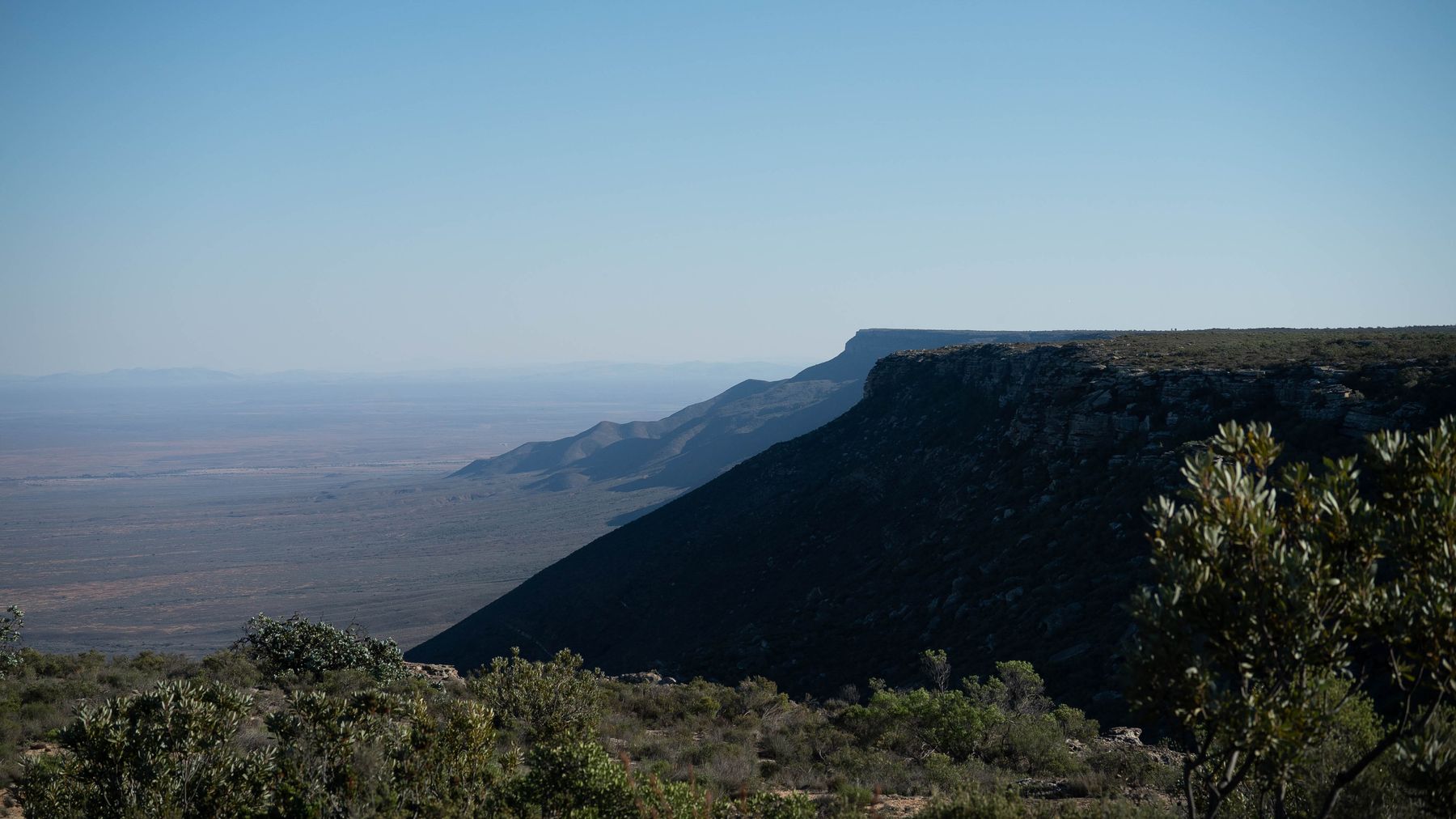 A dark cliff of the escarpment with the plain beyond