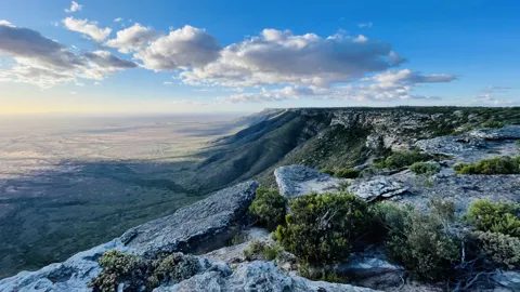 The escarpment edge and the open plains beyond under a cloudy sky