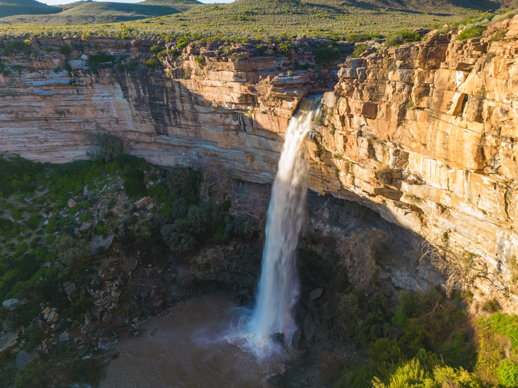 The Nieuwoudtville waterfall dropping over a sandstone edge into a gorge, with green veld above